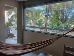 a hammock in a room with a large window at Pousada Laguna in Jacumã