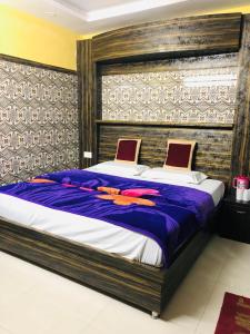 - une chambre avec un grand lit et des draps violets dans l'établissement Vidya hotel, à Katra