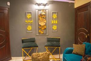 una sala de espera con 2 sillas y una pared con pinturas en Cottage Hotel, en Karachi