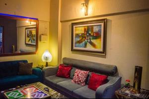sala de estar con sofá gris y almohadas rojas en Cottage Hotel, en Karachi