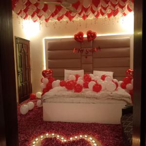 1 dormitorio con 1 cama con globos rojos y blancos en Cottage Hotel, en Karachi