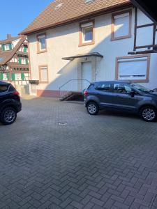 two cars parked in a parking lot in front of a house at Appartement En Allemagne près de Strasbourg in Willstätt