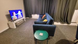 uma sala de estar com um sofá azul e uma televisão em Garland Modern Spacious Flat, London em Londres