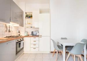 eine Küche mit weißen Schränken sowie einem weißen Tisch und Stühlen in der Unterkunft Appartamento76 in Florenz