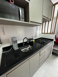 a kitchen counter with a sink and a microwave at Laguna Airbnb 1706B in Sao Paulo