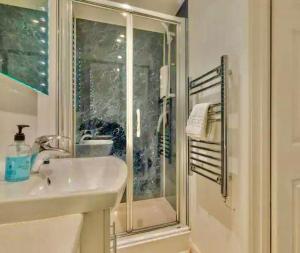 a white bathroom with a shower and a sink at Cambridge City Centre Studio, Sleeps 3 in Cambridge