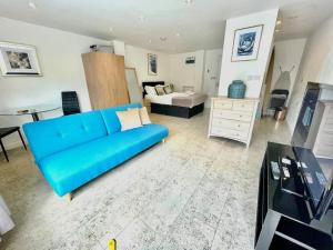 a living room with a blue couch and a bedroom at Cambridge City Centre Studio, Sleeps 3 in Cambridge