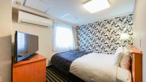 a hotel room with a bed and a flat screen tv at APA Hotel Osaka-Tanimachi in Osaka