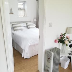 um quarto com uma cama com lençóis brancos e almofadas em Maes Hyfryd em Gaerwen