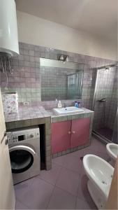 a bathroom with a washing machine and a sink at CozyNest Apartments in Tirana