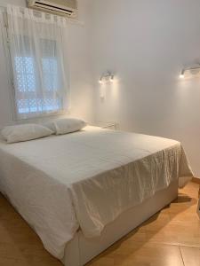 Cama blanca en habitación con ventana en Bonito y tranquilo apartamento en Nervión, en Sevilla