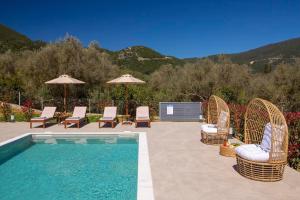 a swimming pool with chairs and umbrellas next to at Christdilia villas in Palaiokatoúna