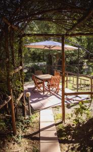 un patio con mesa y sillas bajo una sombrilla en Nature & Relax in Tuscany - Fresco 2, en Roccastrada