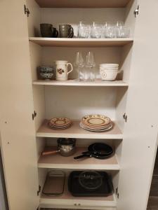 a cupboard with plates and wine glasses and dishes at Peaceful suite near the lake in Victoria