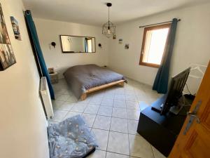 1 dormitorio con 1 cama y TV en el suelo de baldosa en Villa Coccinella, en Les Omergues