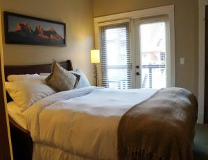 a bedroom with a large white bed with a window at Gracie's Place in Canmore