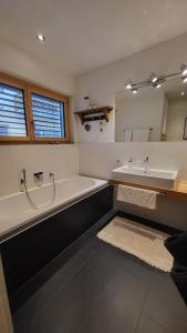 ein Badezimmer mit einer Badewanne, einem Waschbecken und einem Spiegel in der Unterkunft Chasa Scandella - Apartment Carl in Sent