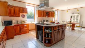 una cocina con armarios de madera y una isla en el centro en Casa Familiar la Tortuga, en Heredia
