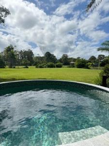 a swimming pool with a view of a field at Lake Weyba Cottages Noosa in Peregian Beach