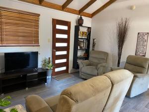 a living room with a couch and chairs and a television at Dongara Breeze Inn in Dongara