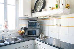 a kitchen with a sink and a clock on the wall at Cozy love nest near the Eifel Tower in Paris