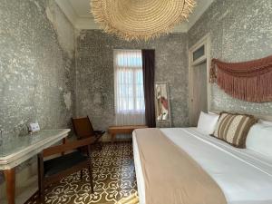 a bedroom with a bed and a desk and a chandelier at Historic House Hotel boutique in Mérida
