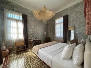 a bedroom with a large bed and a chandelier at Historic House Hotel boutique in Mérida