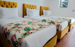 2 Betten in einem Hotelzimmer mit weißen Decken in der Unterkunft Hotel Encanto in Manizales