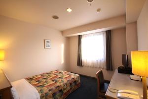 una camera d'albergo con un letto, una scrivania e una finestra di Hotel Ermou Regency a Numazu Altre 31 foto