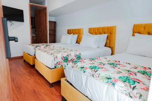 two beds in a hotel room with a tv at Hotel Encanto in Manizales