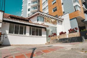 a white building with a sign on the side of it at Hotel Encanto in Manizales