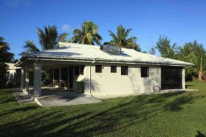 a small white house with palm trees in a field at Are Kapakapa in Arutanga