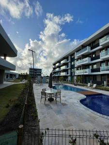 a building with a bench and a table next to a pool at Muro Alto-Porto de Galinhas Flat Makia 104D in Ipojuca