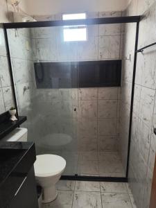 La salle de bains est pourvue d'une douche en verre et de toilettes. dans l'établissement Minha casa fora de casa, à João Pessoa