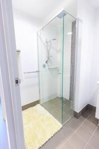 a glass shower in a bathroom with a yellow rug at Central Getaway, On Rundle St in Adelaide