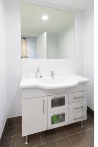 a white bathroom with a sink and a mirror at Central Getaway, On Rundle St in Adelaide