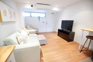 a living room with a white couch and a flat screen tv at Central Getaway, On Rundle St in Adelaide