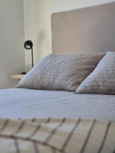 a bed with a white comforter and a pillow at BHIaparts-Roca con COCHERA in Bahía Blanca
