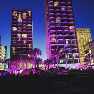 a tall purple building with palm trees in front of it at Ocean Front 53 Steps in Myrtle Beach