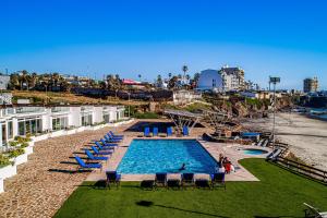 a swimming pool with people sitting in chairs next to a beach at Casa Aquamarina 43 - Playa Arcangel in Rosarito
