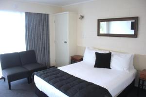 Habitación de hotel con cama y silla en Kapiti Gateway Motel en Waikanae