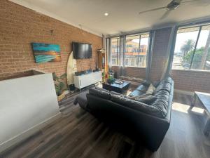 a living room with a leather couch in a brick wall at The Entrance Backpackers in The Entrance