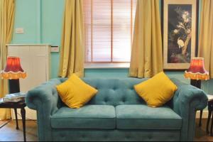 ein blaues Sofa mit gelben Kissen im Wohnzimmer in der Unterkunft Traveller's Rest - Cosy cottage in heart of Wilton in Salisbury + 26 Fotos