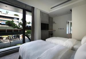 una camera da letto con due letti e una grande finestra di CityInn Hotel Plus- Fuxing North Road Branch a Taipei