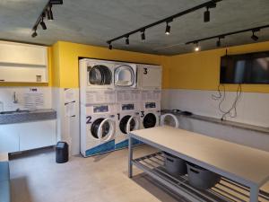a laundry room with two washing machines and a table at Studio Liberdade in São Paulo