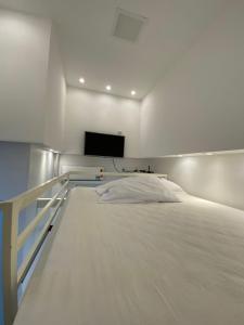 a white bedroom with a bed and a flat screen tv at POUSADA TORRE FORTE ac in Rio Branco