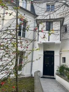 a white house with a black door and a tree at Relax 1 bedroom apartment - EG01 in Enghien-les-Bains