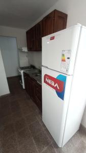 Un refrigerador blanco en una cocina con gabinetes de madera. en COMPLEJO MAINUMBI BARRIO Hipotecario, en Mercedes