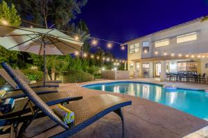 una piscina con sillas y una sombrilla junto a un edificio en Scottsdale Desert Dream Estate Resort Style Lounging, Palm Trees, Pool & Hot Tub, Putting Green, en Phoenix