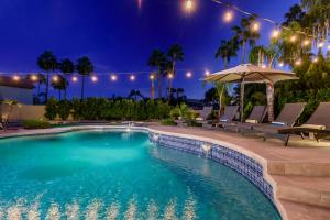 una piscina por la noche con sillas y sombrilla en Scottsdale Desert Dream Estate Resort Style Lounging, Palm Trees, Pool & Hot Tub, Putting Green, en Phoenix